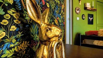 A golden rabbit sculpture on a wooden surface, a vibrant floral wall mural, and a green wall with various decorative items.