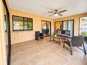 Ein geräumiger Patio-Bereich mit Deckenventilator, Esstisch und Korbmöbeln.