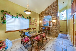 A dining area with a stone wall, a chandelier, and a window with blinds. - Tuscany at Shaver Lake -3BR Mountain Escape (Shaver Lake)