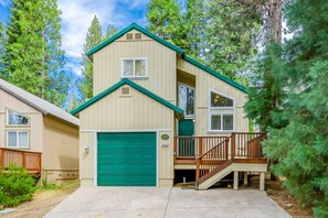 A two-story house with a green garage door, a small porch with a wooden railing, and a visible address number. - Tuscany at Shaver Lake -3BR Mountain Escape (Shaver Lake)