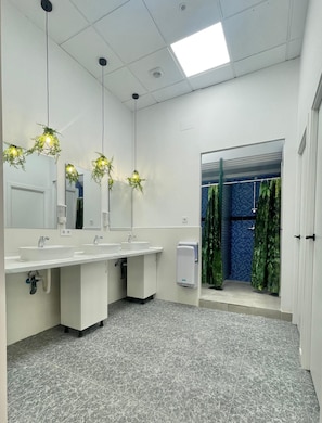Een badkamer met twee wastafels, een spiegel, een handdroger en een douche met groene gordijnen.