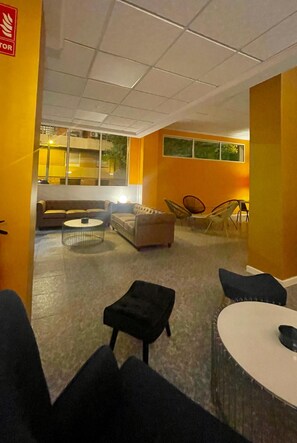 A room with a sofa, chairs, a round table, and a small stool.