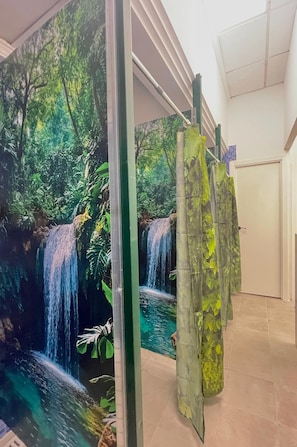Een kamer met een groot muurschildering van een waterval en begroeiing, een deur en een betegelde vloer.