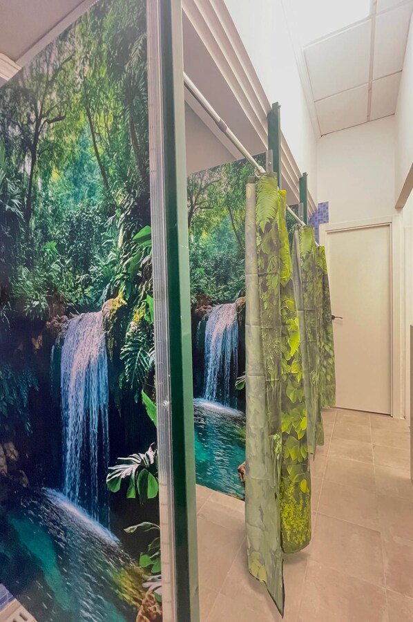 A room with a large mural of a waterfall and greenery, a door, and a tiled floor. - UWANT HOSTEL UP (San Vicente del Raspeig)