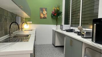 Une cuisine moderne dotée d’un plan de travail en marbre, d’un évier, d’un four à micro-ondes et d’une fenêtre avec des stores.