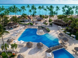 A resort with a large swimming pool, palm trees, and beach umbrellas. - Sunscape Coco Punta Cana - All Inclusive (Punta Cana)