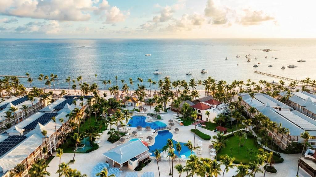 Un resort con varias piscinas, palmeras y vista al océano.