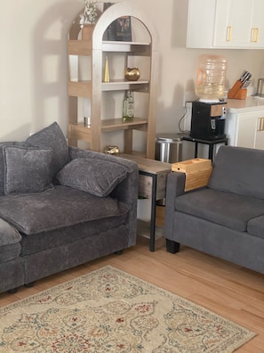 A living room with two grey sofas, a wooden coffee table, a patterned rug, a bookshelf with decorative items, and a water dispenser. - Marvelous 4-bedroom house in Playas de Rosarito perfect for families. (Playas de Rosarito)