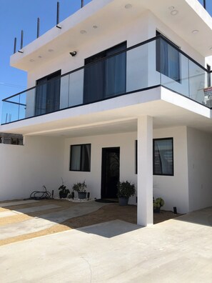 A modern two-story building with a flat roof, large windows, and a balcony. - Marvelous 4-bedroom house in Playas de Rosarito perfect for families. (Playas de Rosarito)