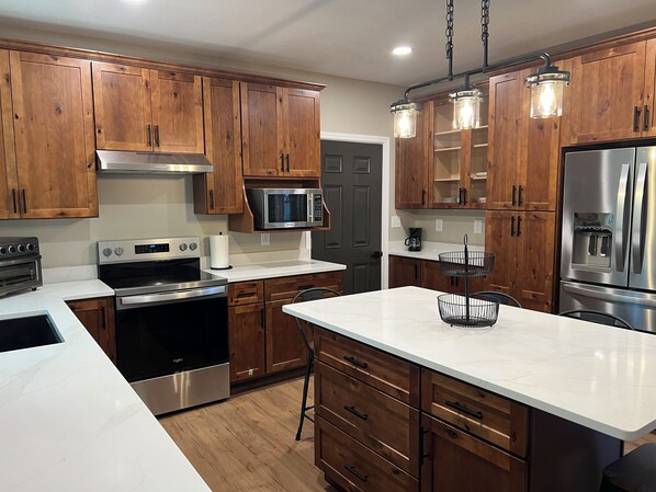 A modern kitchen with wooden cabinets, stainless steel appliances, and a marble countertop.