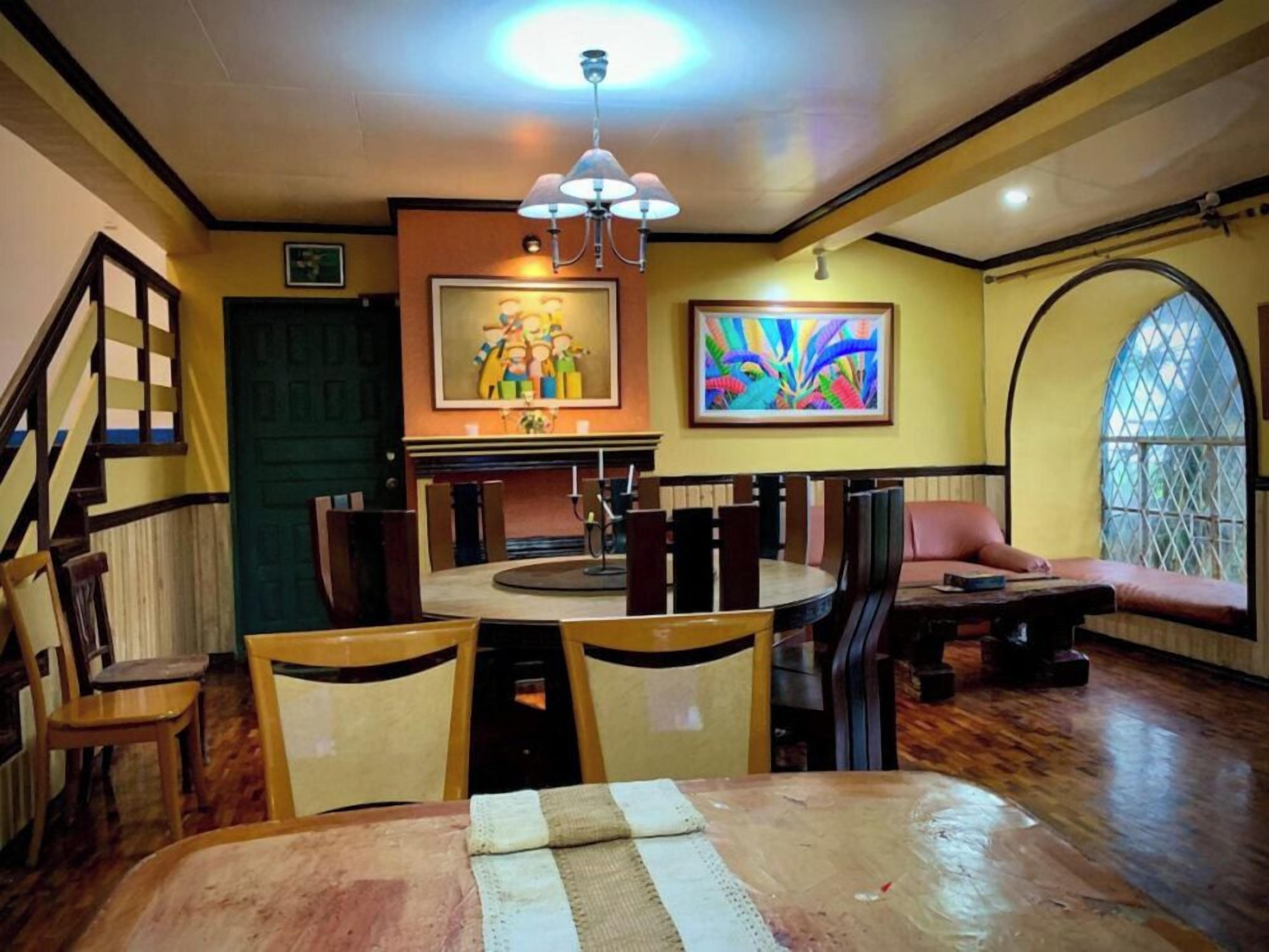 Ein Essbereich mit einem runden Tisch, Stühlen, einer Chandelüster und Kunstwerken an den Wänden.