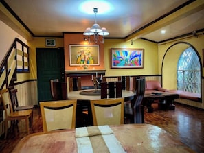 A dining area with a round table, chairs, a chandelier, and artwork on the walls. - Cozy Escape in Baguio (Baguio)