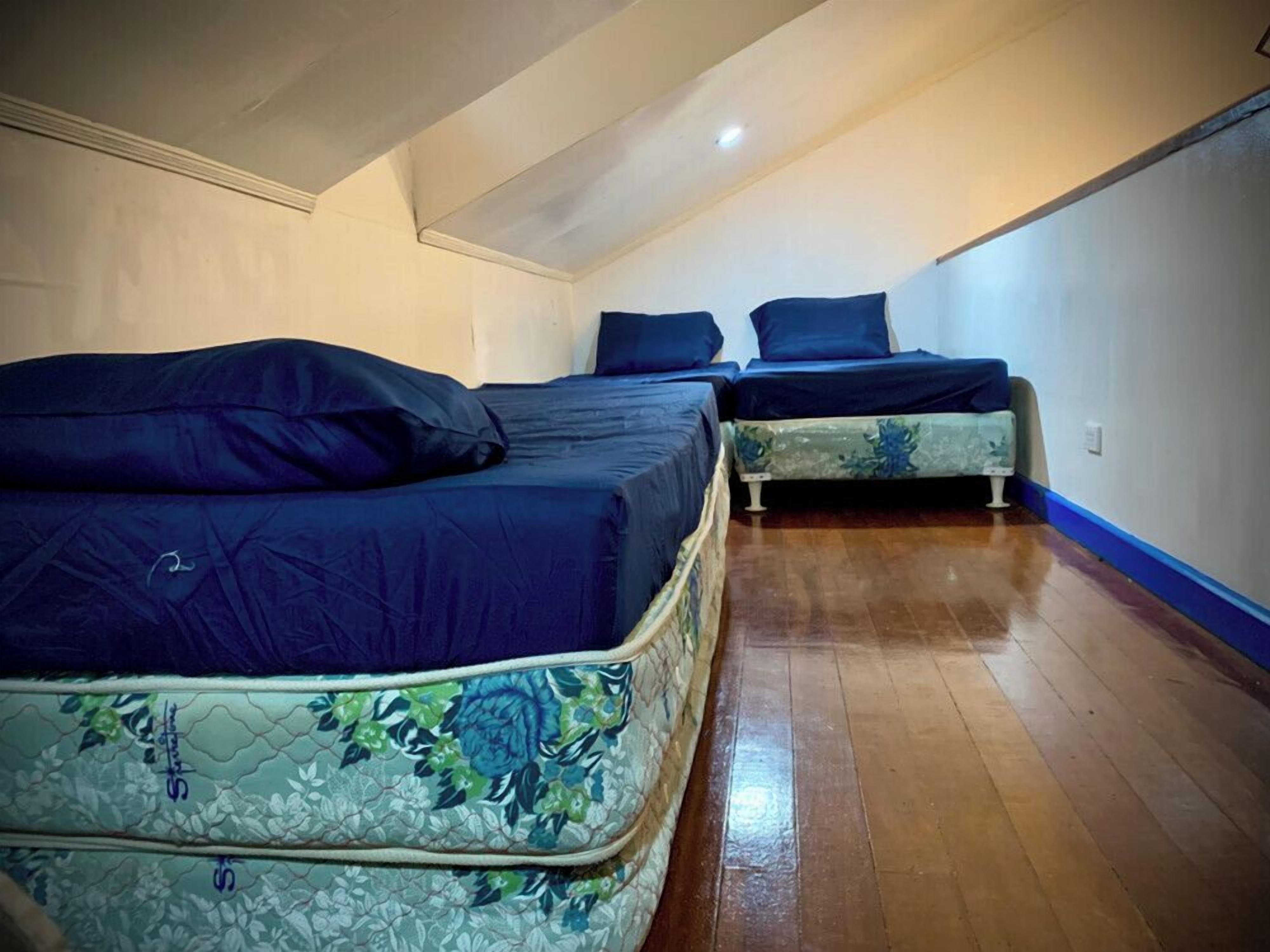 Ein Zimmer mit zwei Betten, Holzboden und schrägen Wänden.
