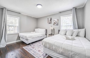 A hotel room with two single beds, a large bed, a nightstand with a lamp, and a patterned rug. - Mins to Airport & Dining- Wonderful in Whitehaven (Memphis)