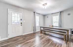 Une pièce avec un banc en bois, une porte blanche et un luminaire au plafond.