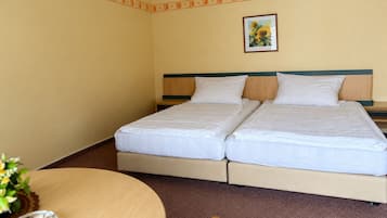 Una habitación de hotel con dos camas, una mesita y un cuadro en la pared.