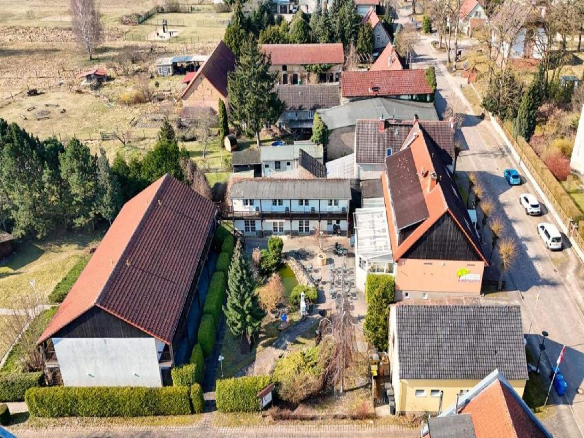 A residential area with multiple houses, a small pond, and a road with parked cars.