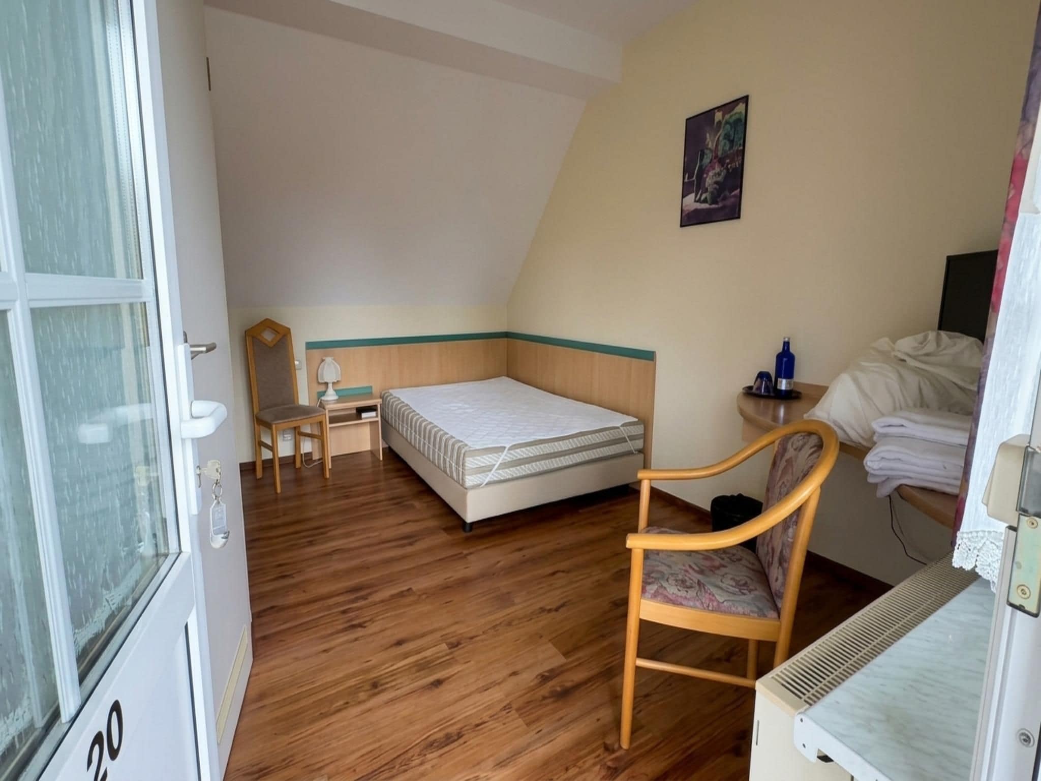 A room with a bed, a chair, a desk, and a radiator.