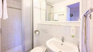 A bathroom with a shower, toilet, sink, and a mirror.