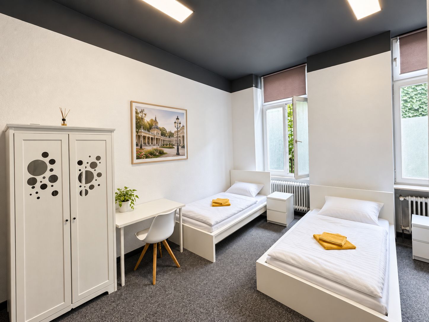 Een slaapkamer met twee bedden, een bureau, een kledingkast en een raam met uitzicht op groen.