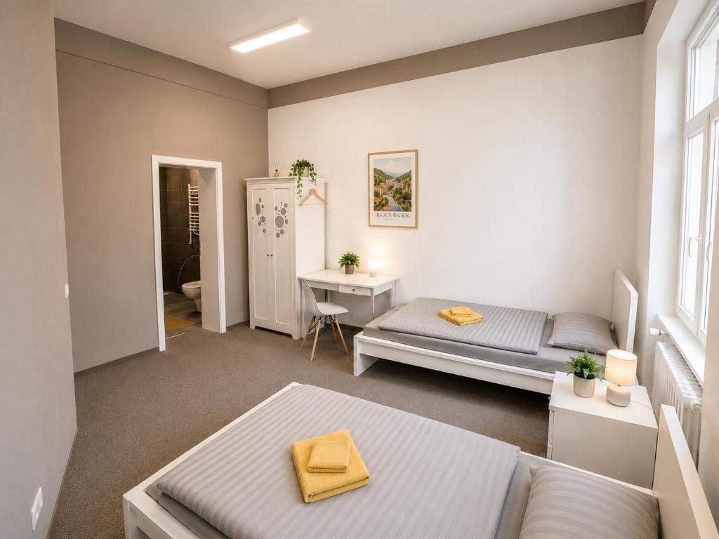 A bedroom with two beds, a desk, a wardrobe, and a window.