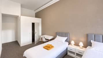 A hotel room with a bed, bedside tables, a desk, and a wardrobe.