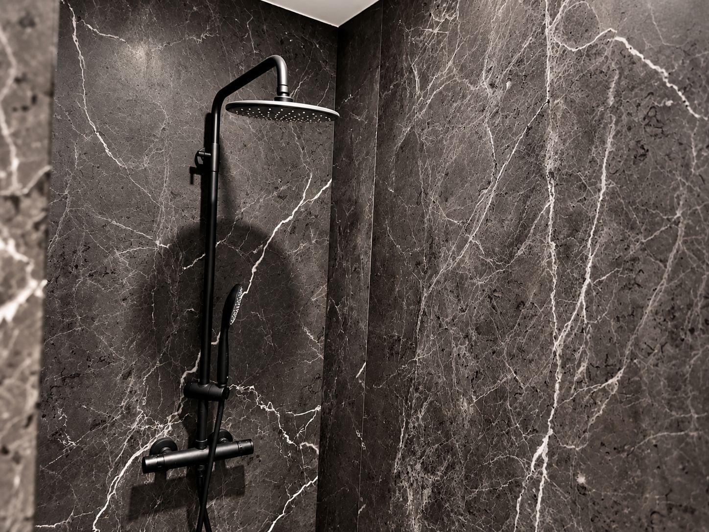 Une salle de bain moderne avec une douche à l’italienne aux parois en marbre noir et un robinet mural.