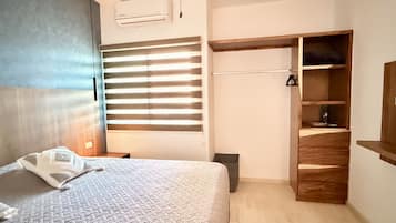 Un dormitorio con cama, armario, ventana con persianas y equipo de aire acondicionado.