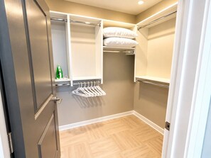 A compact room with a wardrobe, a hanging rack, and a shelf with bottles. - The Birmingham Heights | 2BR Residence (Birmingham)
