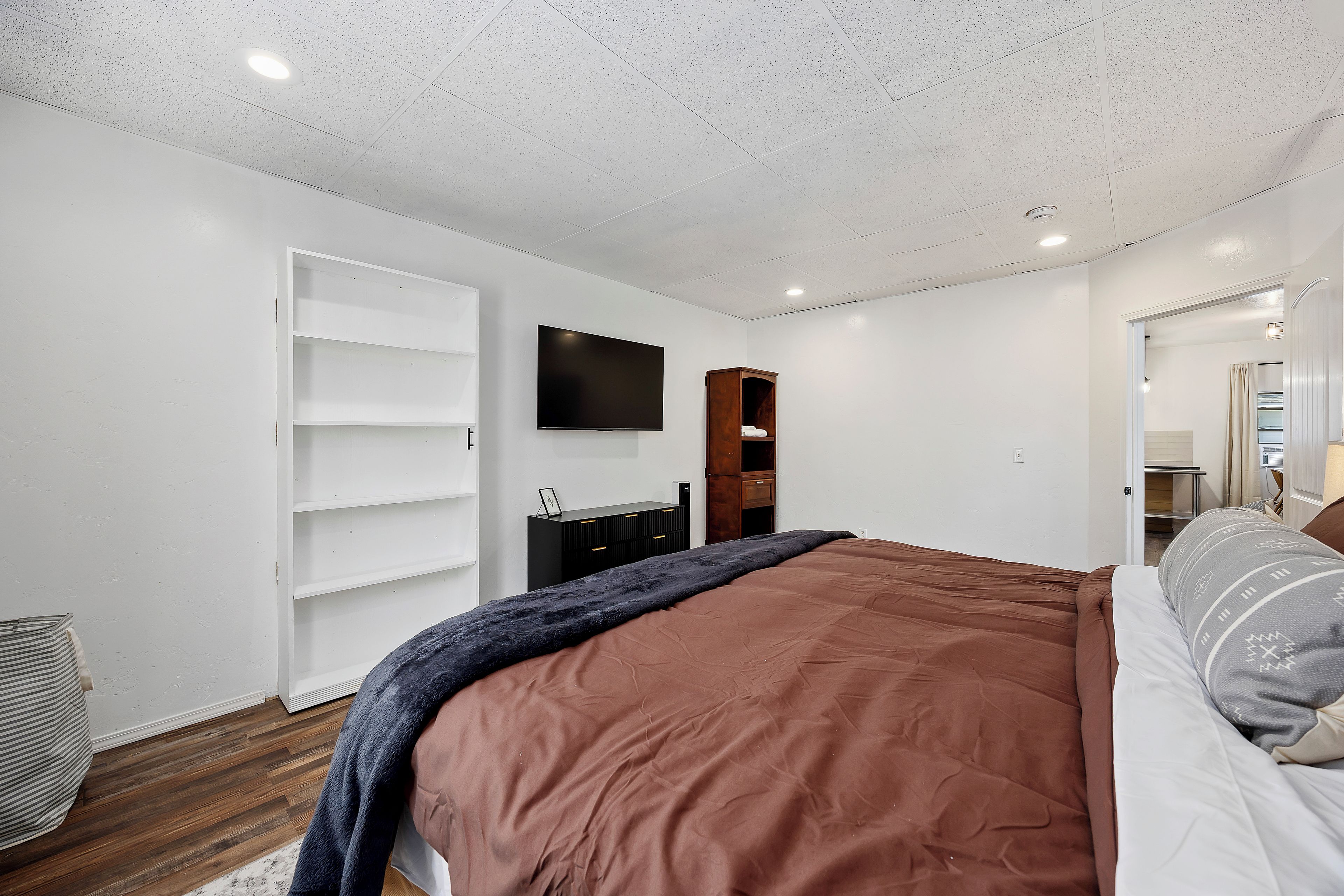 A bedroom with a bed, a TV, a wardrobe, and a desk.