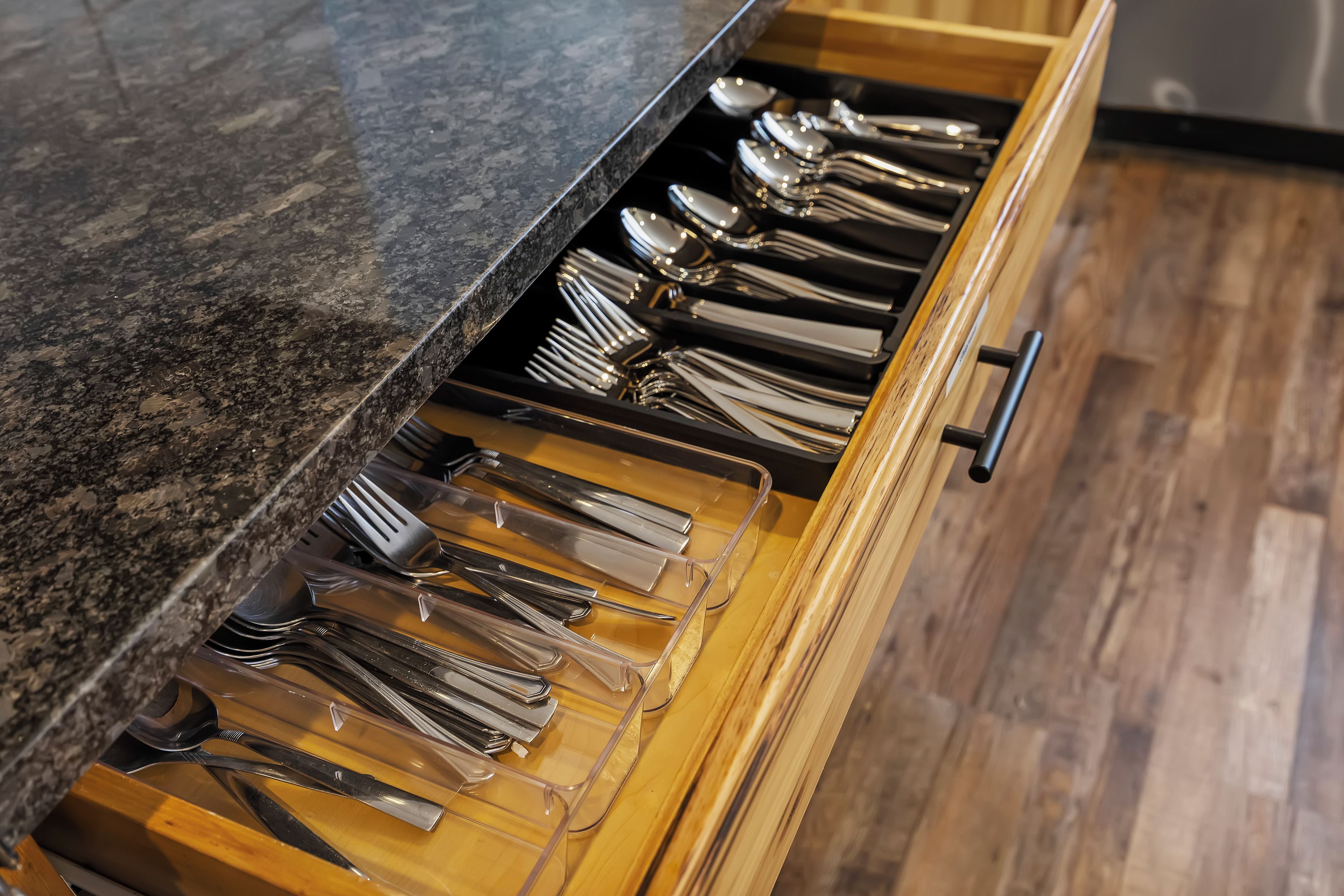 A drawer with multiple compartments containing various utensils.