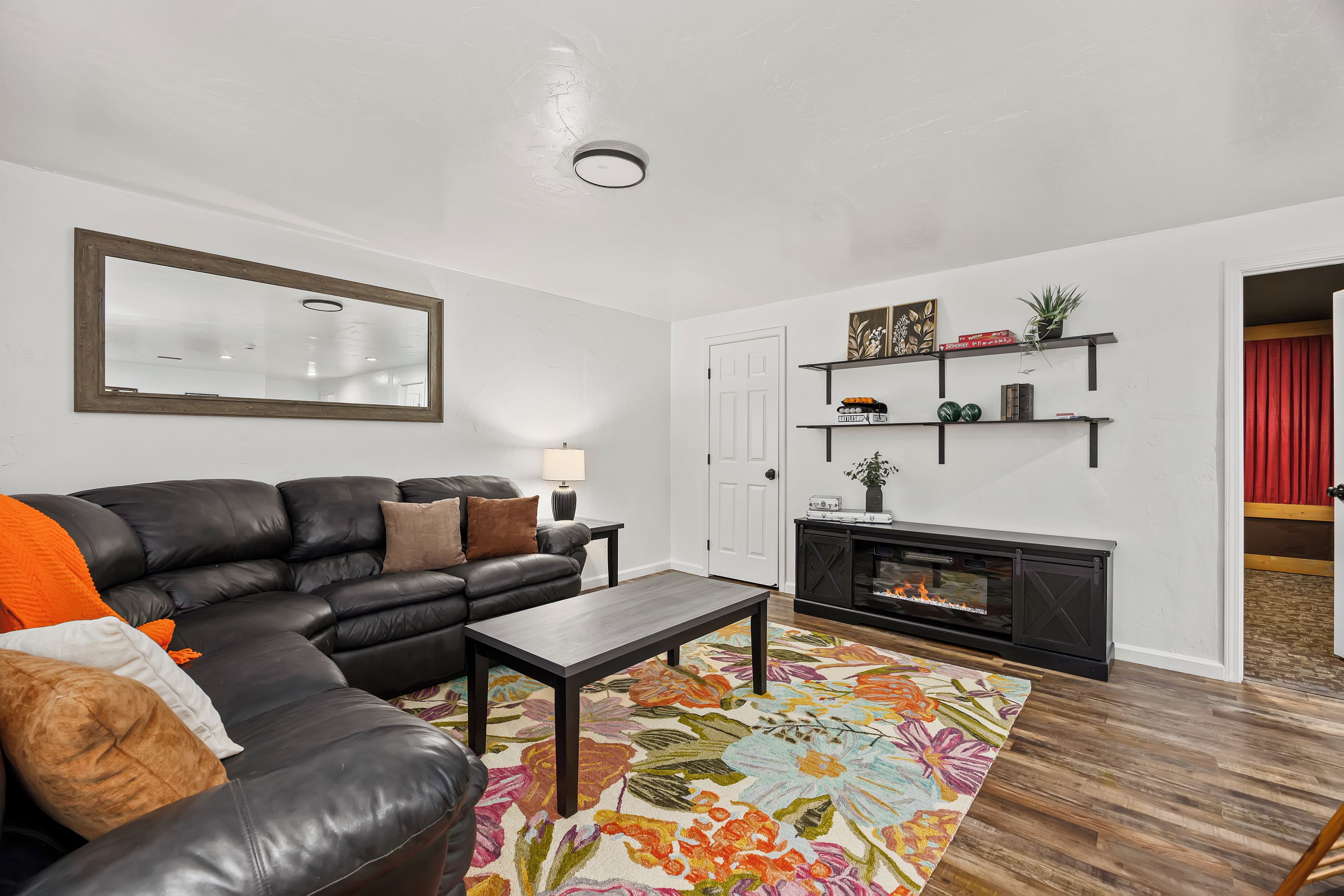 A living room with a black leather sofa, a coffee table, a fireplace, and a floral rug.