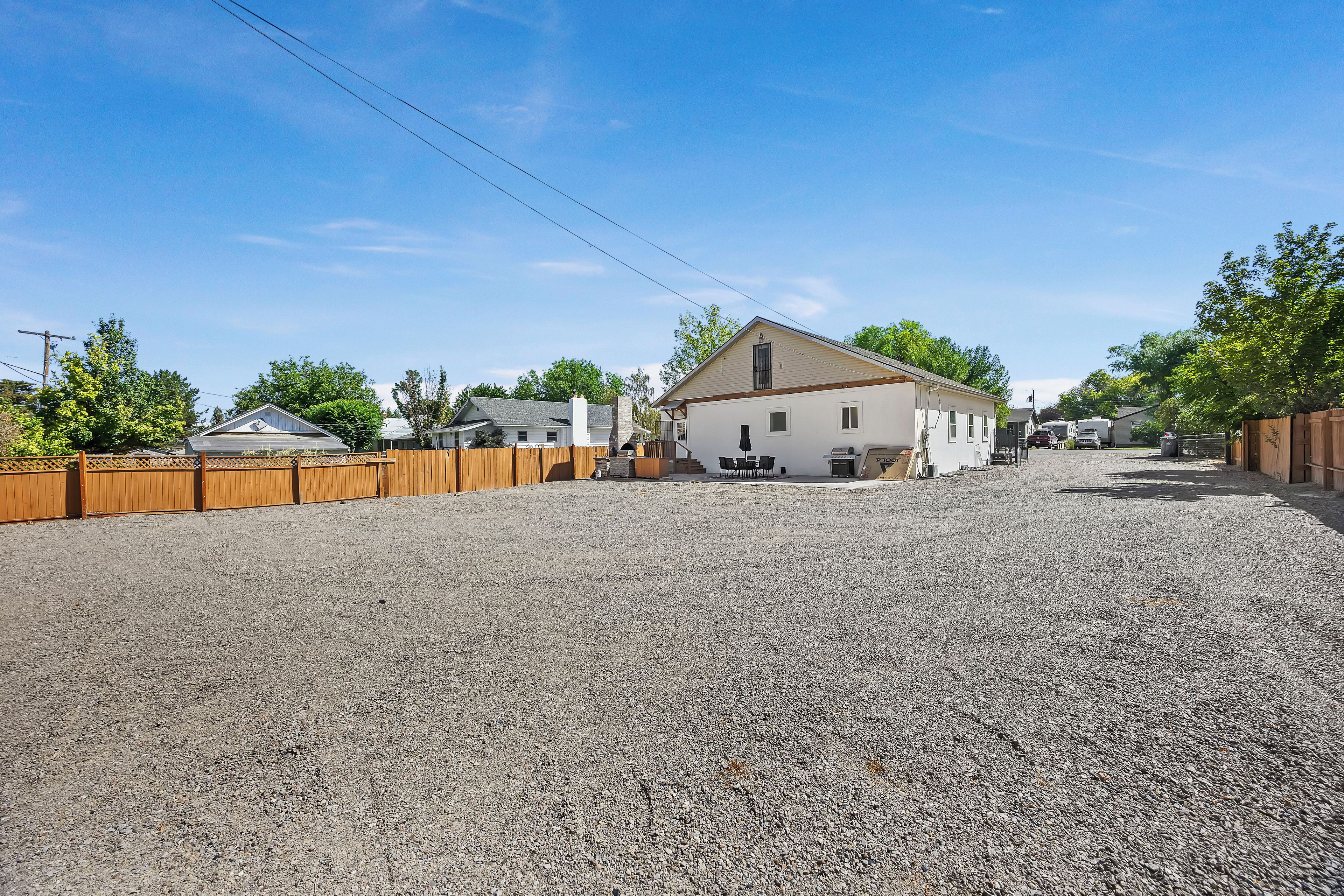 Un barrio residencial con camino de grava, cercas de madera y casas con fachadas blancas.