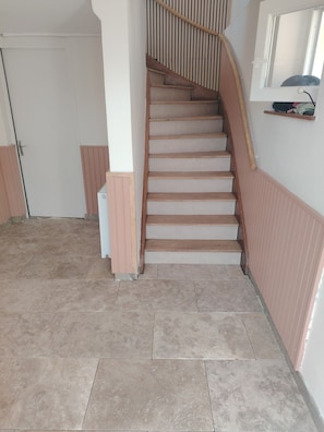 A staircase with wooden steps and a handrail, leading to a door with a white frame. - The Burgundian Interlude (Rigny-sur-Arroux)