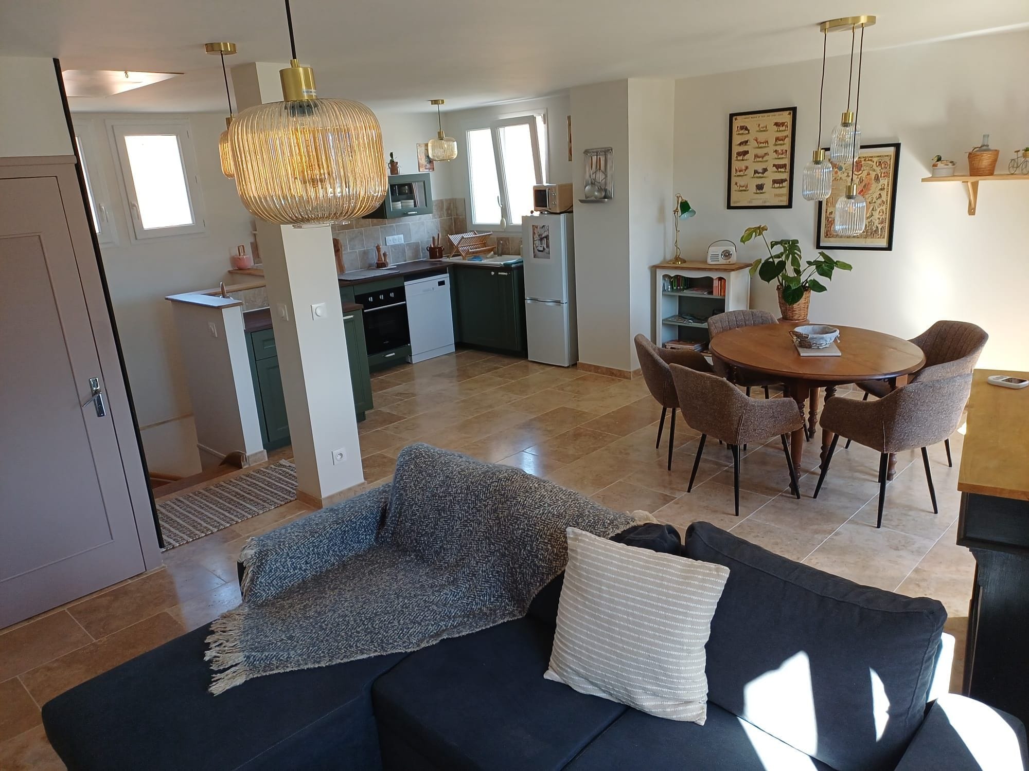 Un salon moderne avec un canapé foncé, une table basse et un coin repas comprenant une table ronde et des chaises.