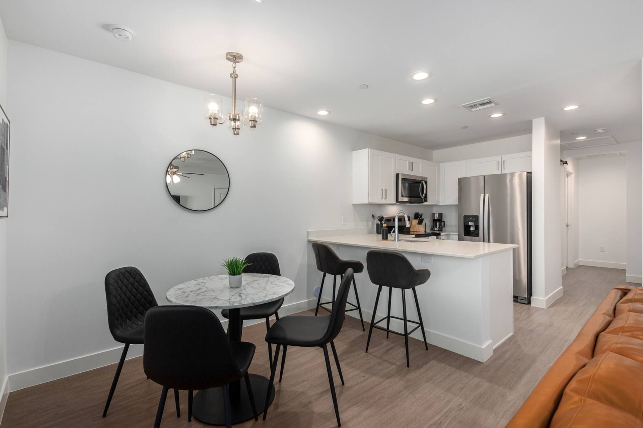 A modern kitchen with white cabinets, a stainless steel refrigerator, and a marble countertop.