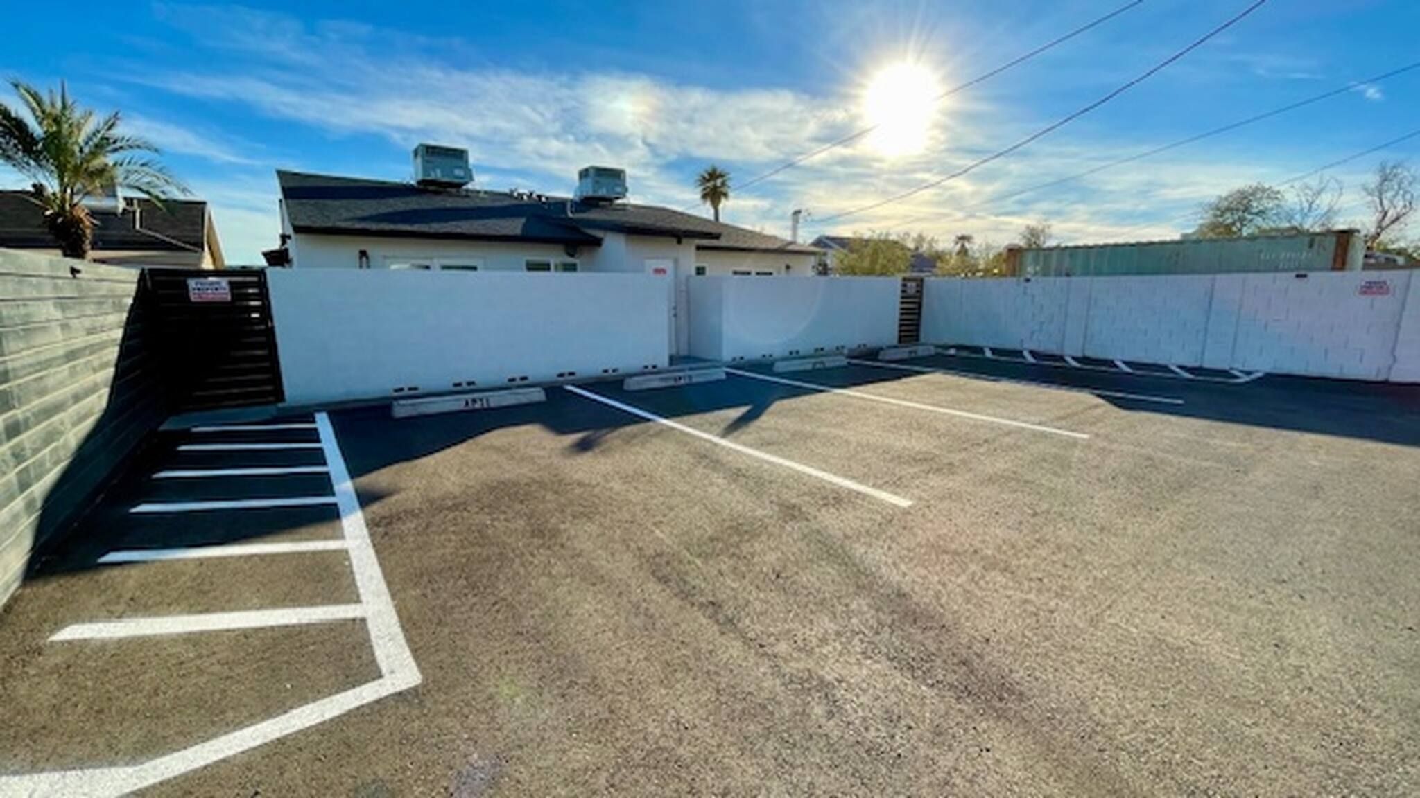 Un parking avec des places délimitées et un bâtiment doté d’un toit plat et de bouches d’aération.