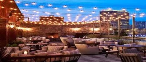 An outdoor seating area with multiple sofas and chairs, a checkered floor, and string lights.