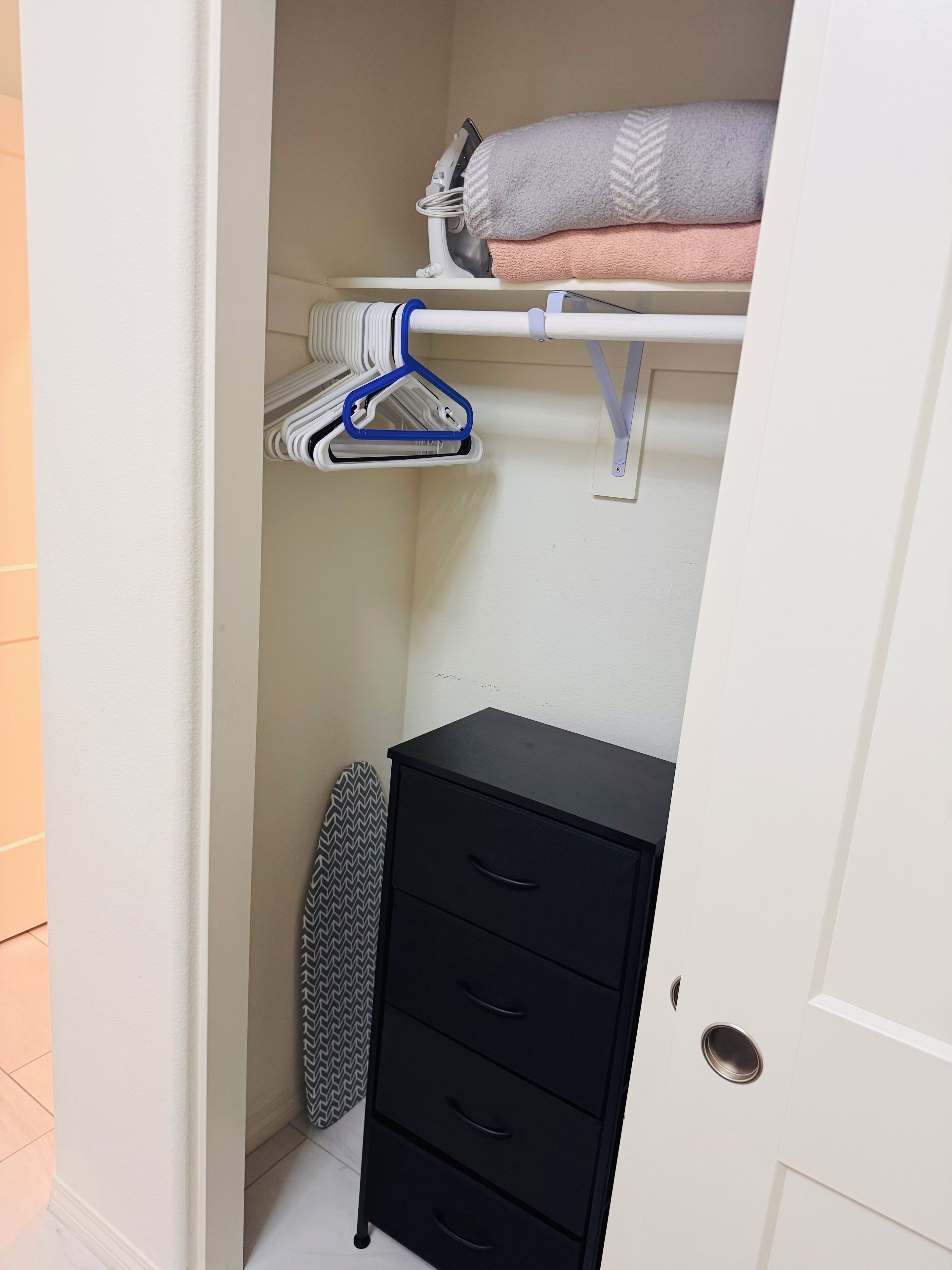 A closet with hanging space, a shelf, and a storage unit.