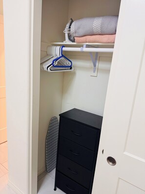 A closet with hanging space, a shelf, and a storage unit.