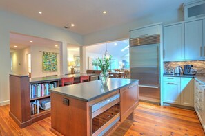 A modern kitchen with a central island, built-in appliances, and a dining area with a view. - Renovated Sea Pines Retreat with Private Pool (Hilton Head Island)