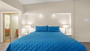 A bedroom with a large bed, two bedside lamps, and a mirror. - Desert Days Studio | Pool + Private Patio (Palm Springs)