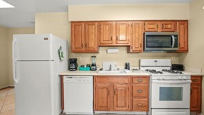 A kitchen with wooden cabinets, a refrigerator, a microwave, a stove, and a dishwasher. - Desert Days & Poolside Ways | 1BR Suite (Palm Springs)
