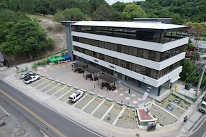 Un edificio de varios pisos con techo plano, ventanas amplias y una zona de estar al aire libre en la planta baja.