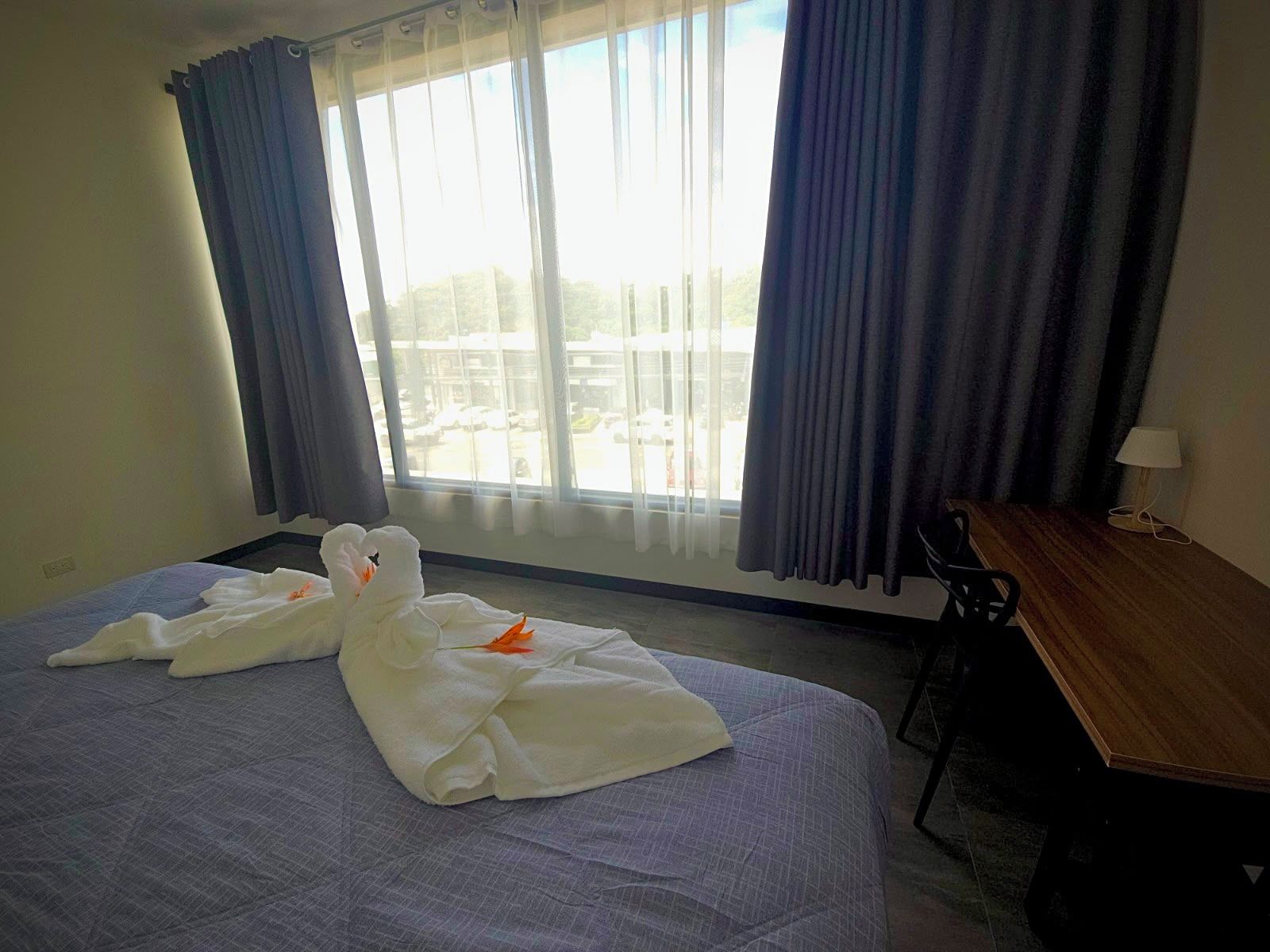 Ein Hotelzimmer mit Bett, Schreibtisch und Blick nach draußen.
