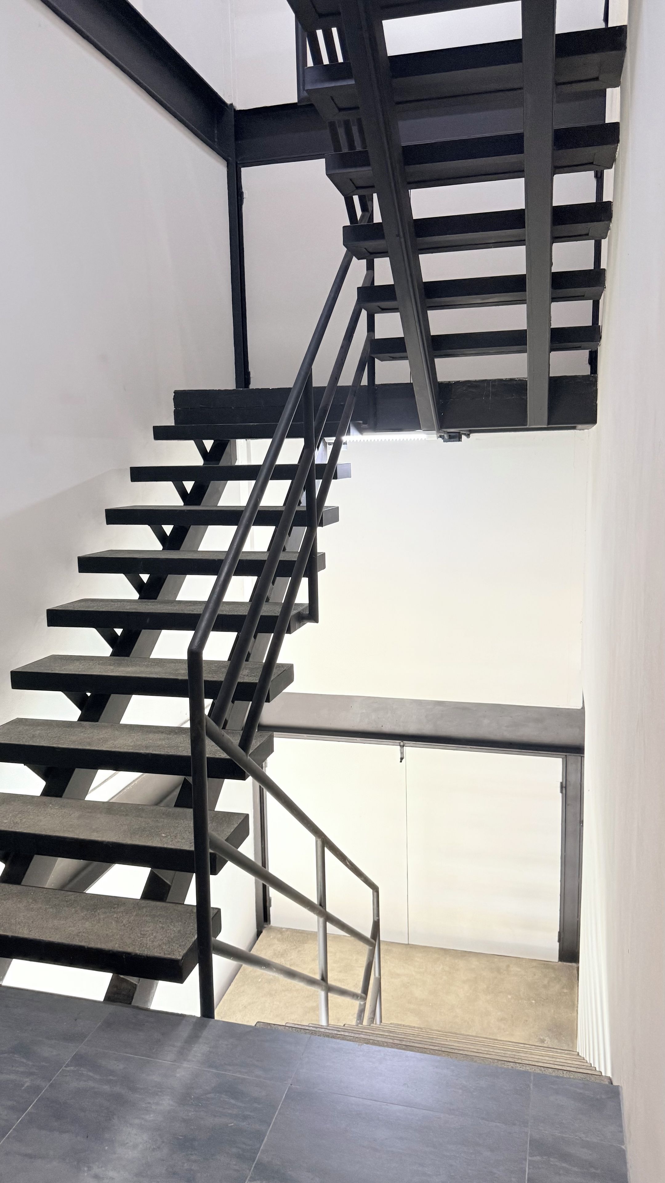 Escada moderna com corrimão de metal e piso de concreto.
