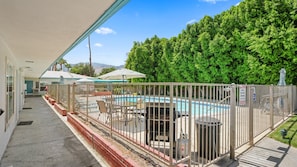A fenced pool area with a patio table and chairs, a trash can, and a closed gate. - Palm Springs Poolside Escape that Sleeps 4 (Palm Springs)