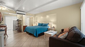A bedroom with a bed, bedside tables, a nightstand, a sofa, and a dining area with chairs. - Joshua Tree & Chill | Palm Springs Studio (Palm Springs)