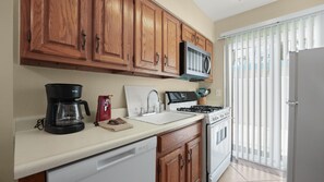 A kitchen with wooden cabinets, a microwave, a coffee maker, a sink, and a dishwasher. - Joshua Tree & Chill | Palm Springs Studio (Palm Springs)