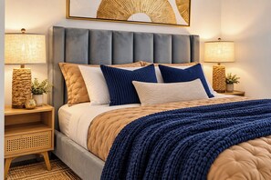 A neatly made bed with a tufted headboard, flanked by bedside lamps and a woven lamp base. - Luxury Skyline Studio in Downtown Miami (Miami)